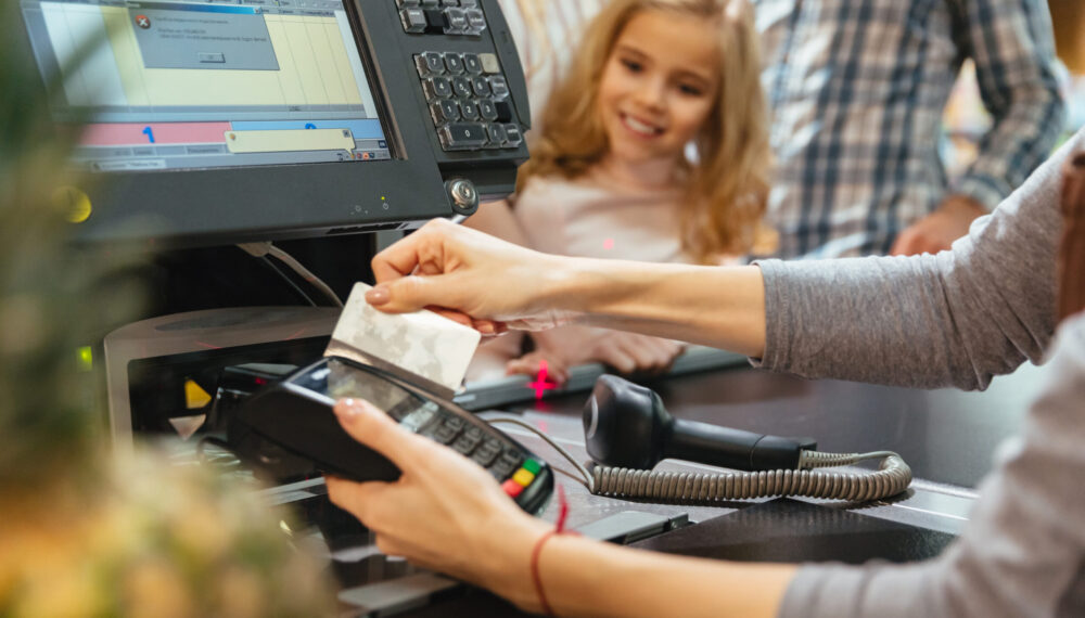 Female staff using credit card terminal at cash counter in supermarket