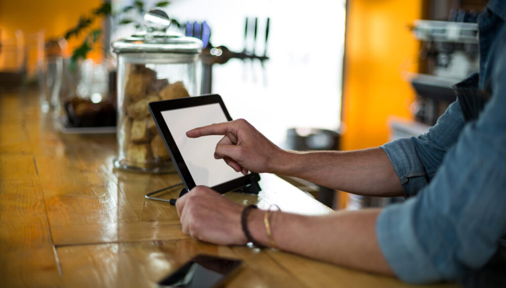 Waiter standing at counter using digital tablet in cafÃ©