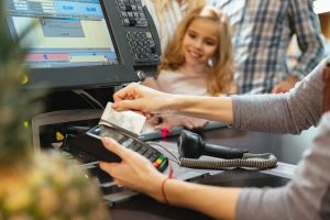 Female staff using credit card terminal at cash counter in supermarket