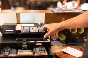 Shot in low light hand pressing electronic cash register in a shop