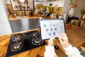 Woman holding digital tablet with running smart home application, controlling kitchen devices remotely. close-up on device screen